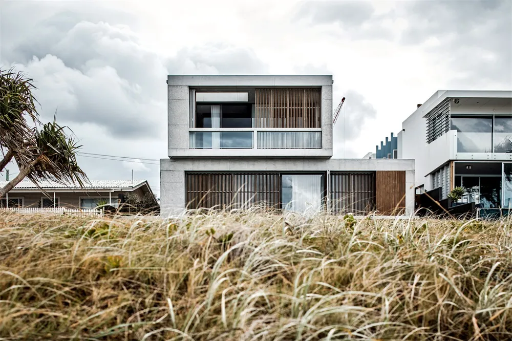 A two-story residential house with a modern design, constructed primarily of concrete, featuring large glass windows and a co