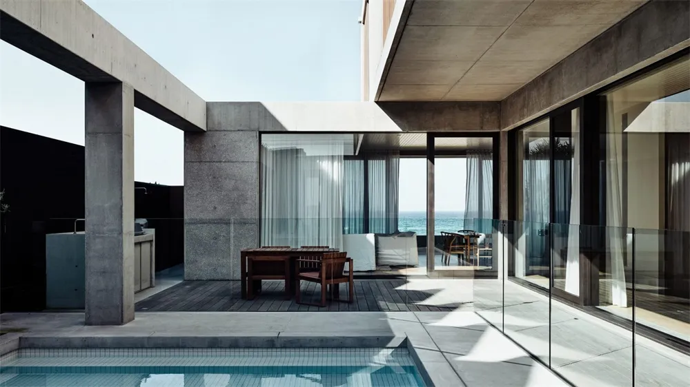Modern minimalist residential exterior featuring concrete, glass, and a swimming pool.