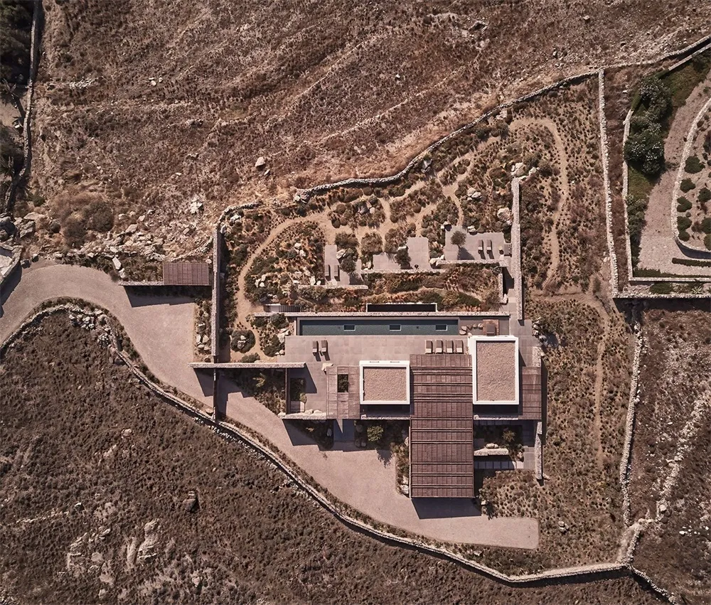 A modern residential building with a clay tile roof and an outdoor pool surrounded by desert landscape.