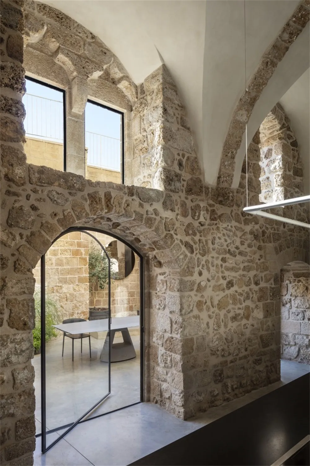 Historic architecture featuring stone walls and a glass door with a modern furniture setup.