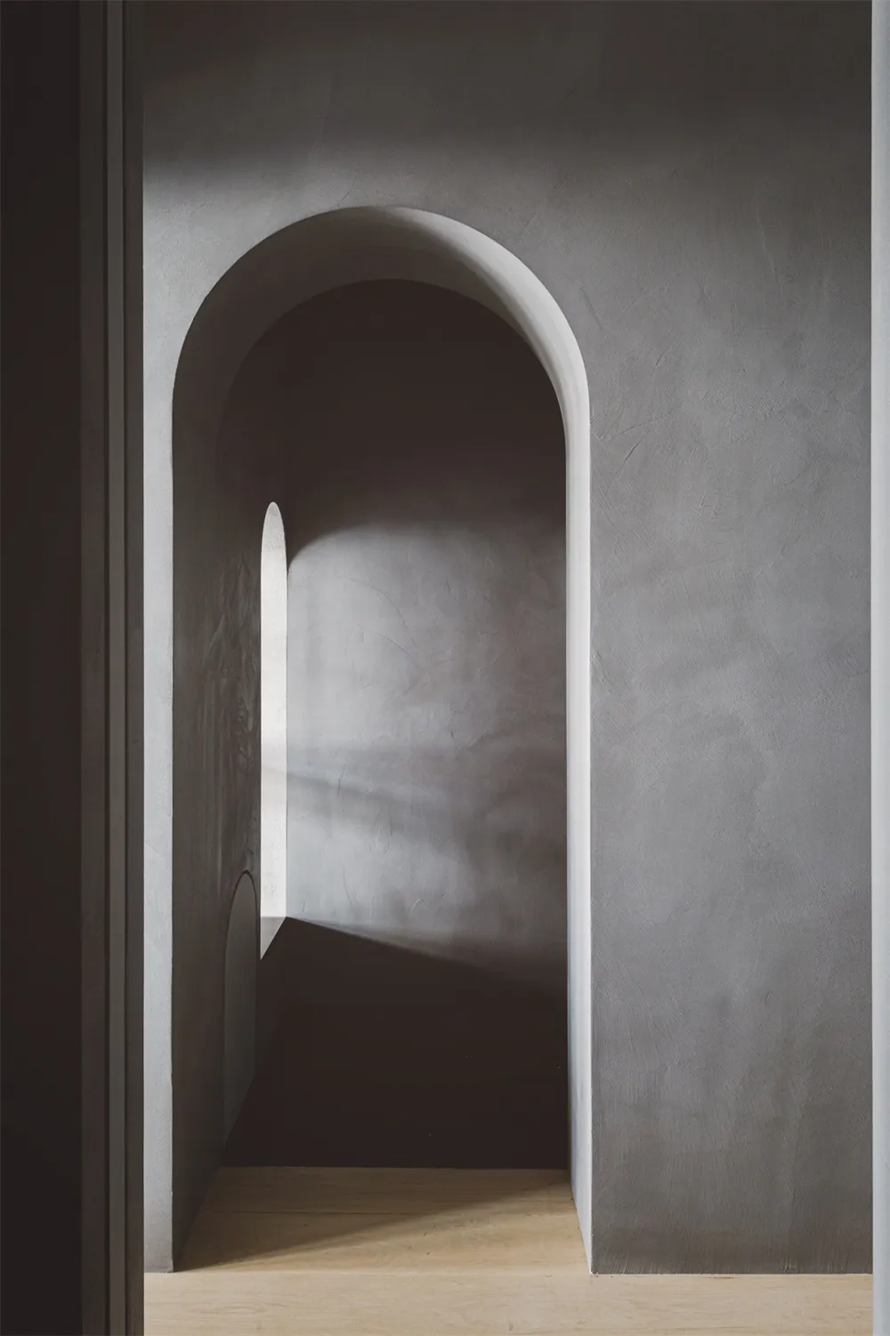 An architectural photograph showcasing a minimalist design with concrete arches.