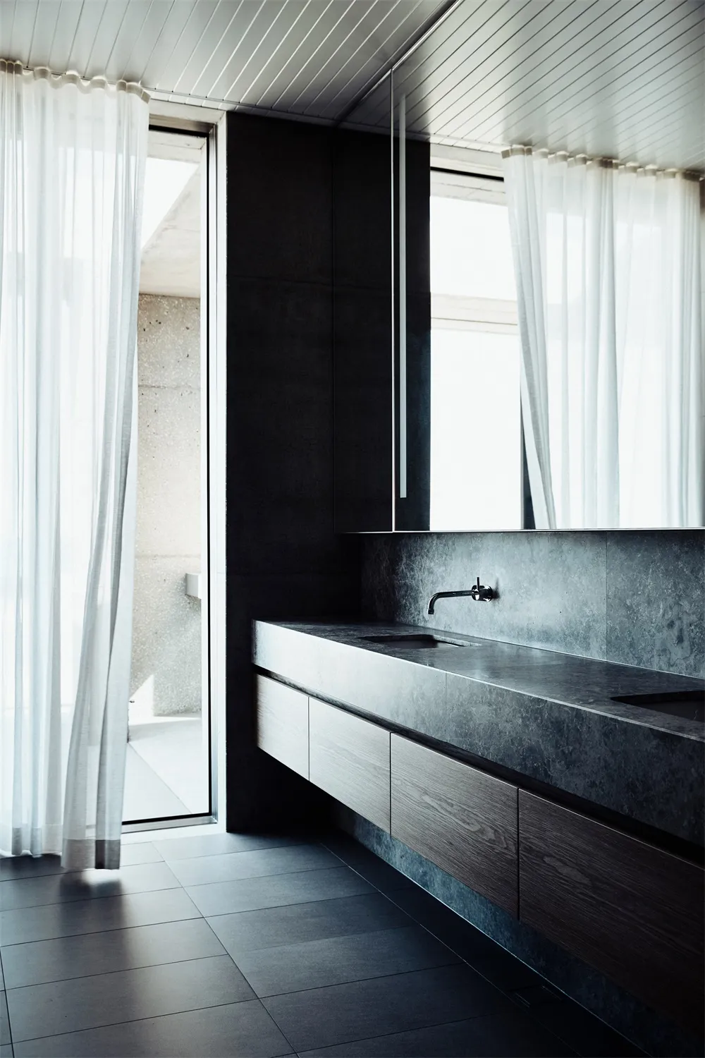 Minimalist modern bathroom featuring concrete materials, with large windows draped in sheer white curtains and a floating van