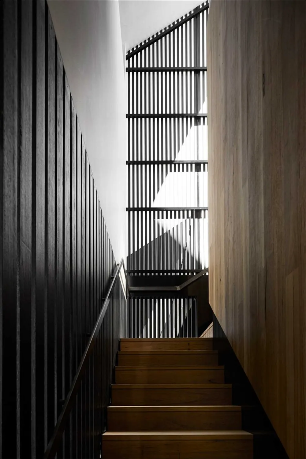 Interior staircase with wooden steps and railings, showcasing modern architectural design.