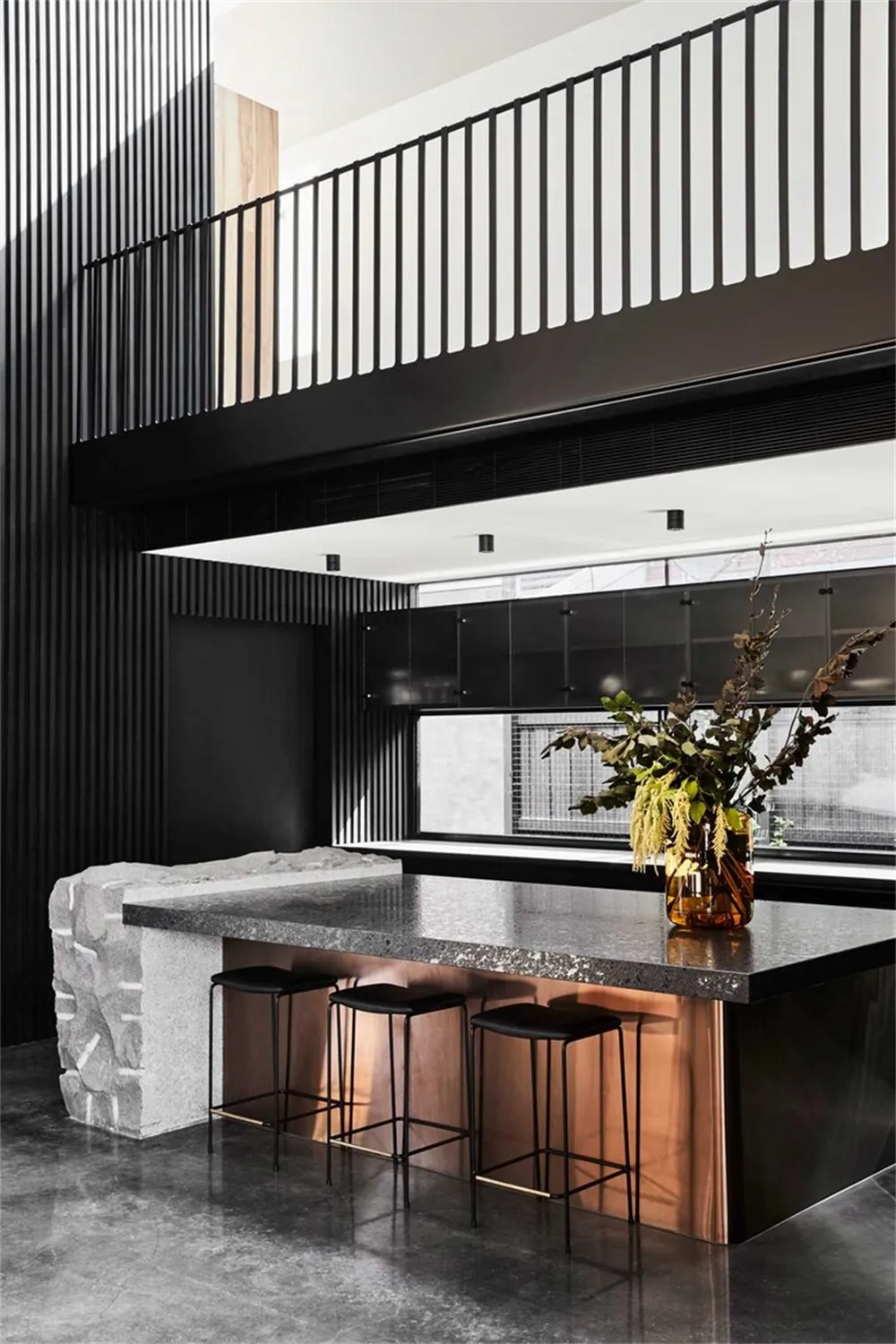 Modern kitchen bar featuring black granite counter and black stools with copper detailing.