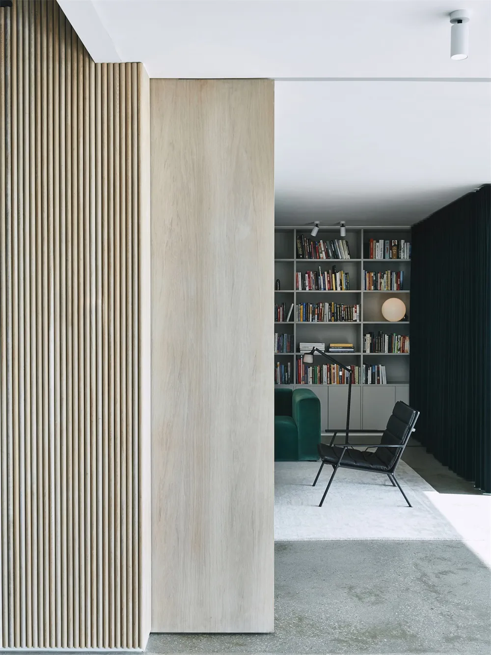 A modern library with wooden paneling and a collection of books on shelves.