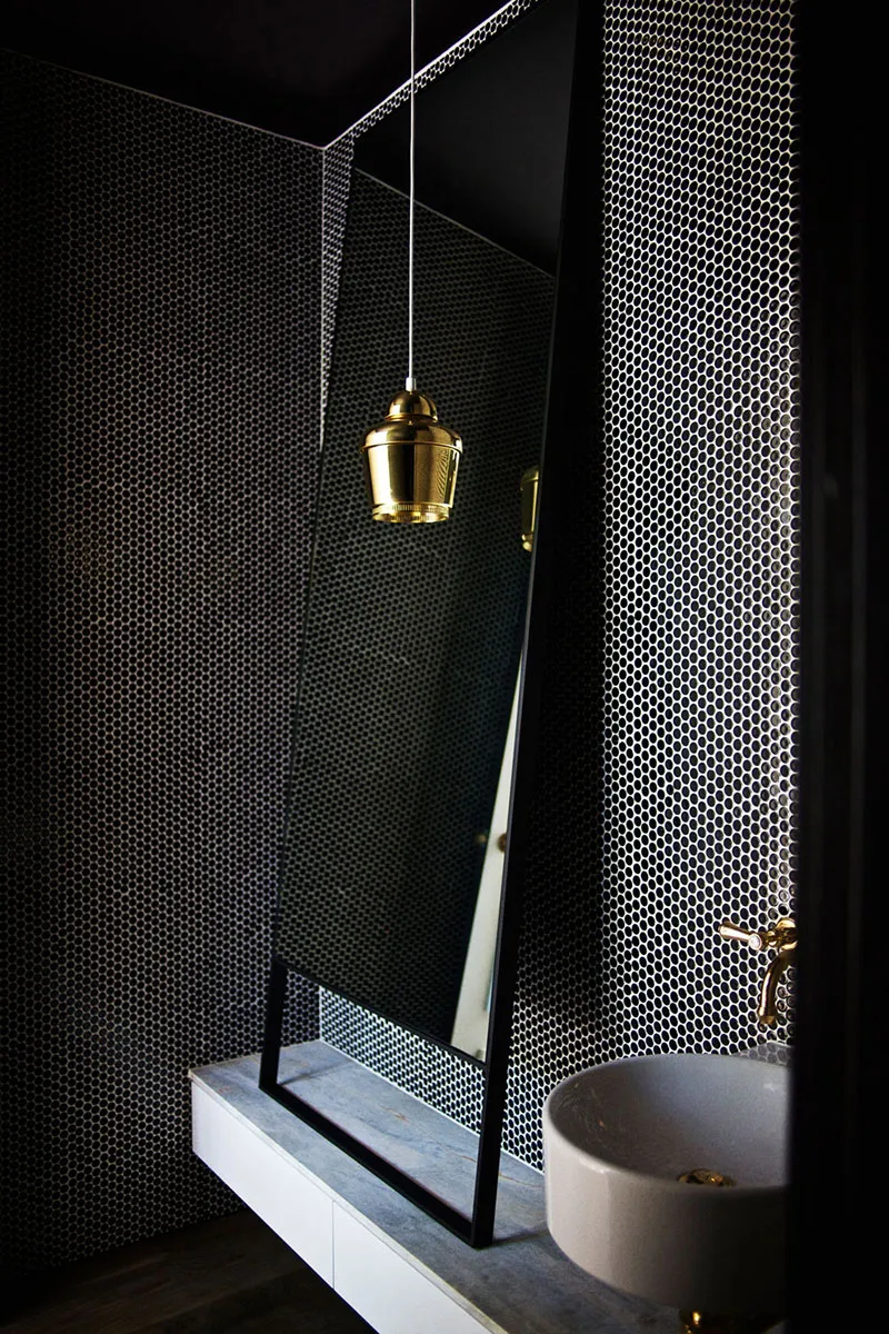 A modern bathroom featuring black and white tiles, a floating vanity, and a round sink.
