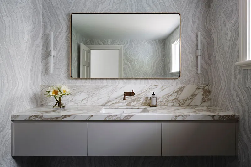 A modern bathroom featuring marble countertops and a sleek vanity.