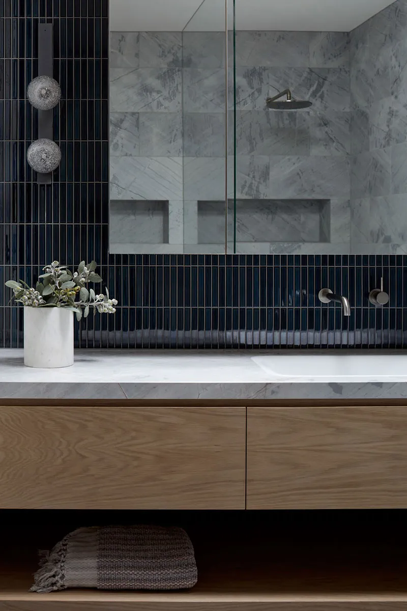 Modern bathroom with marble tiles and floating wooden vanity.