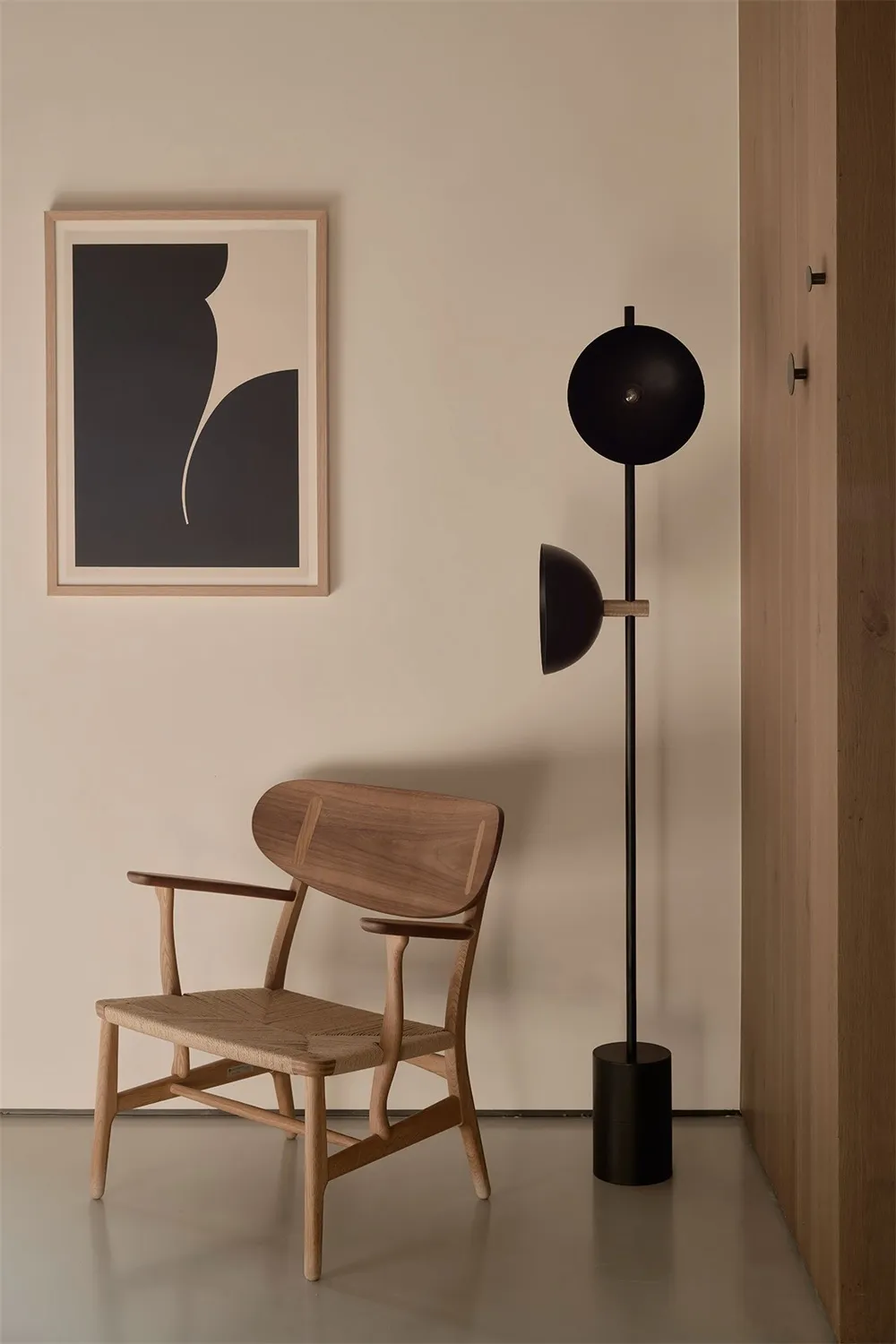 A minimalist living room with a wooden armchair and a black floor lamp.