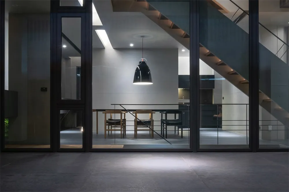 Interior design featuring concrete, glass, and metal materials in a modern living space.
