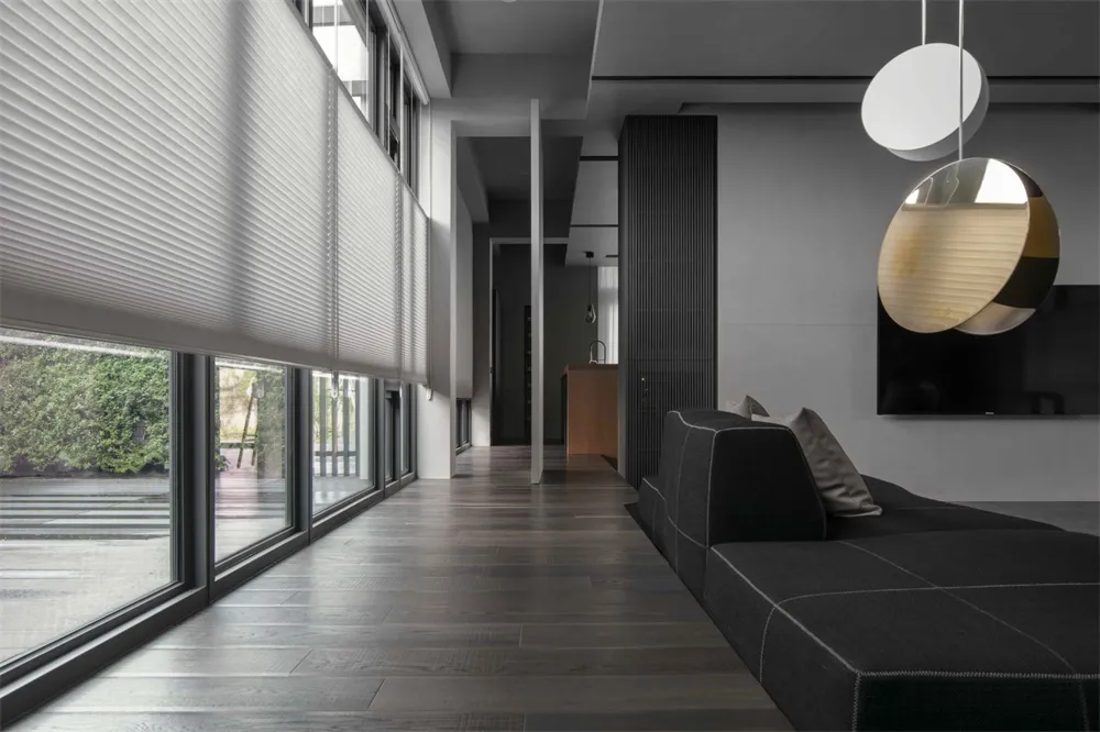 A modern minimalist living room featuring dark wood floors, wall paneling, and a glass divider.