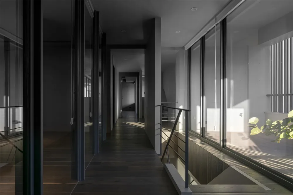 A modern interior hallway with glass walls and dark wooden flooring.