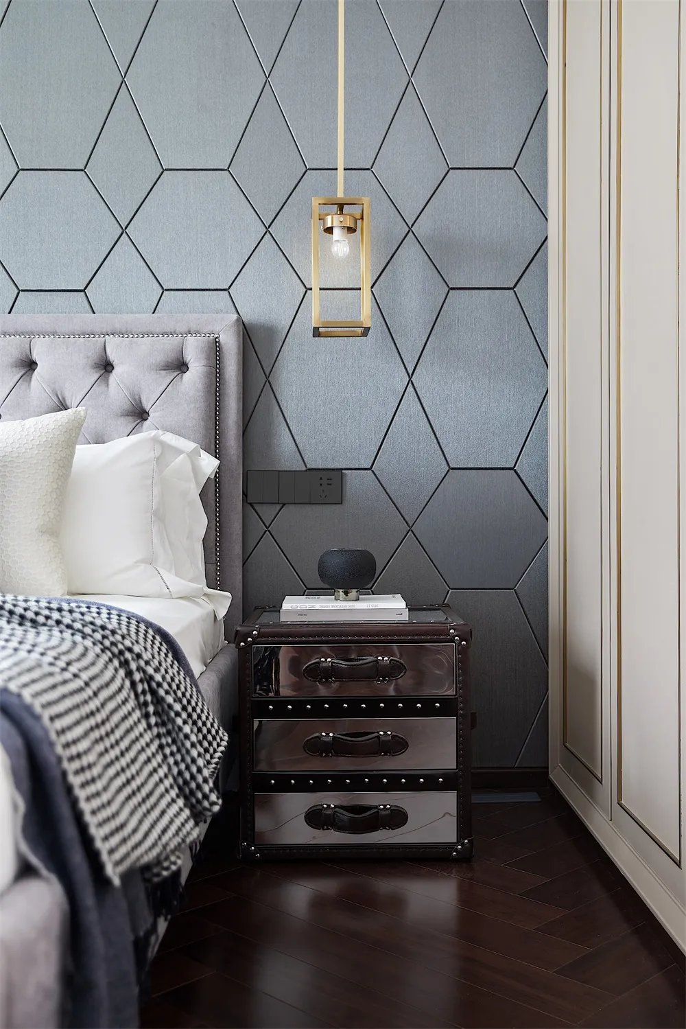 Modern grey bedroom featuring a upholstered headboard and metallic nightstand.