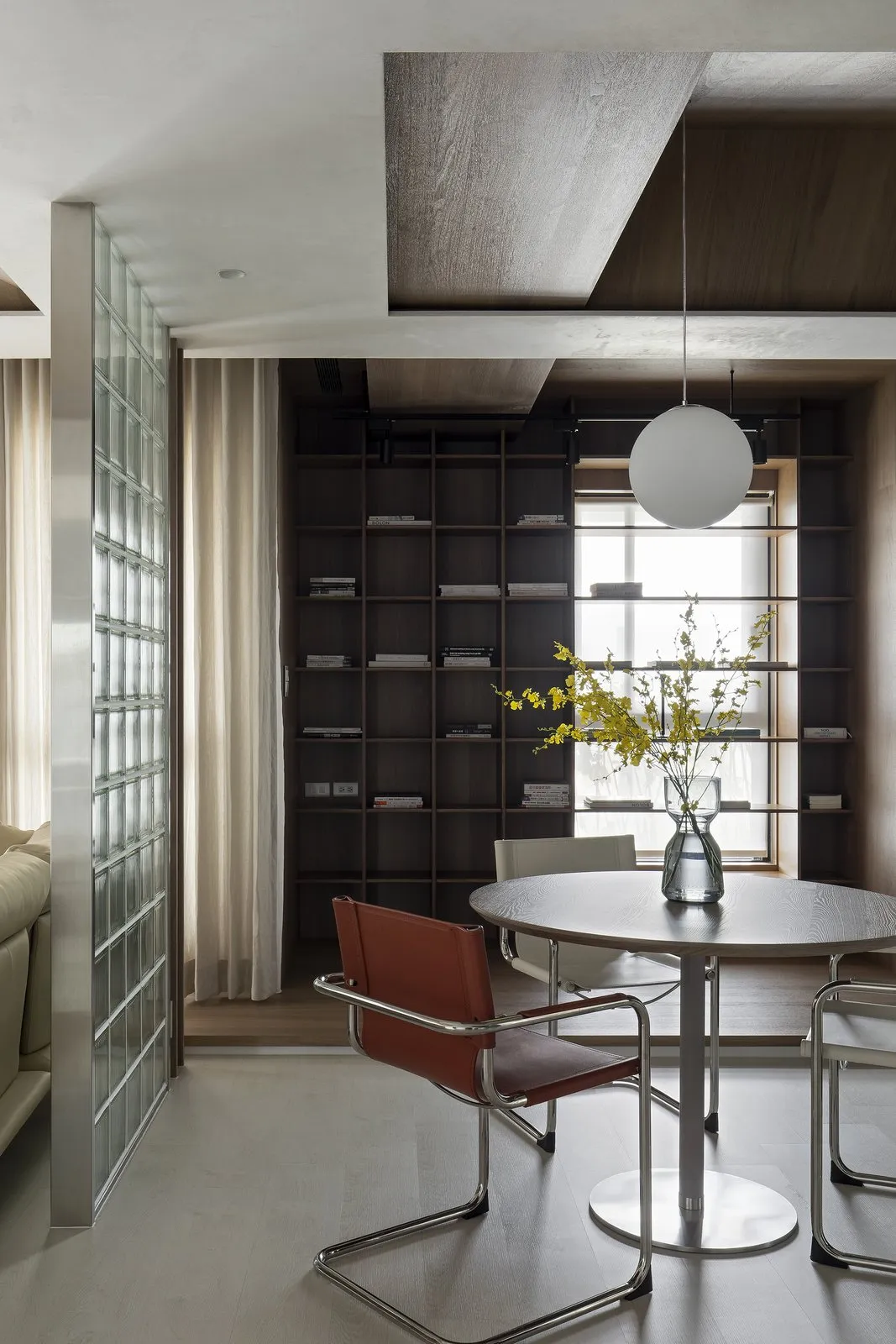 Modern interior featuring a library-office with wooden shelves, glass walls, and metal accents.