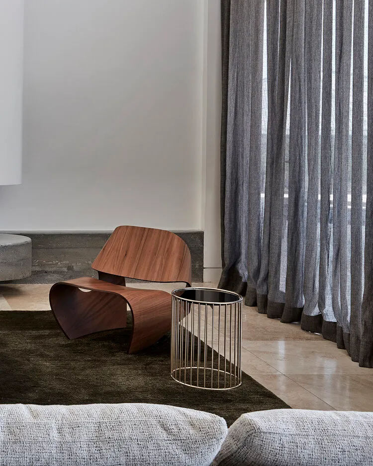 A modern living room featuring a wooden armchair and a metal side table.