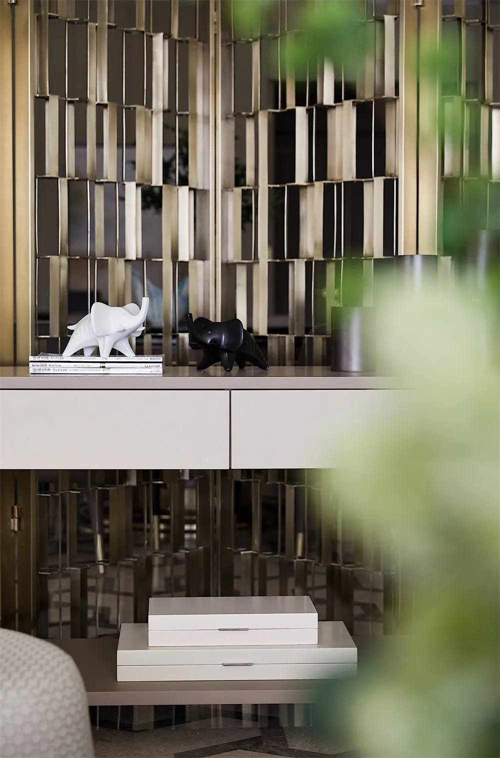 Two ceramic elephant sculptures, one white and one black, placed on top of a white surface with a white ceramic drawer unit.