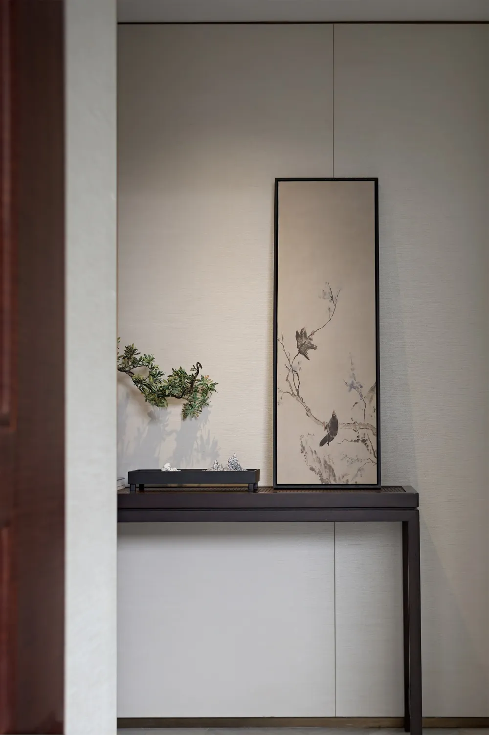 A minimalist console table with a wooden frame and a decorative wallpaper backdrop, featuring a black metal tray holding vari