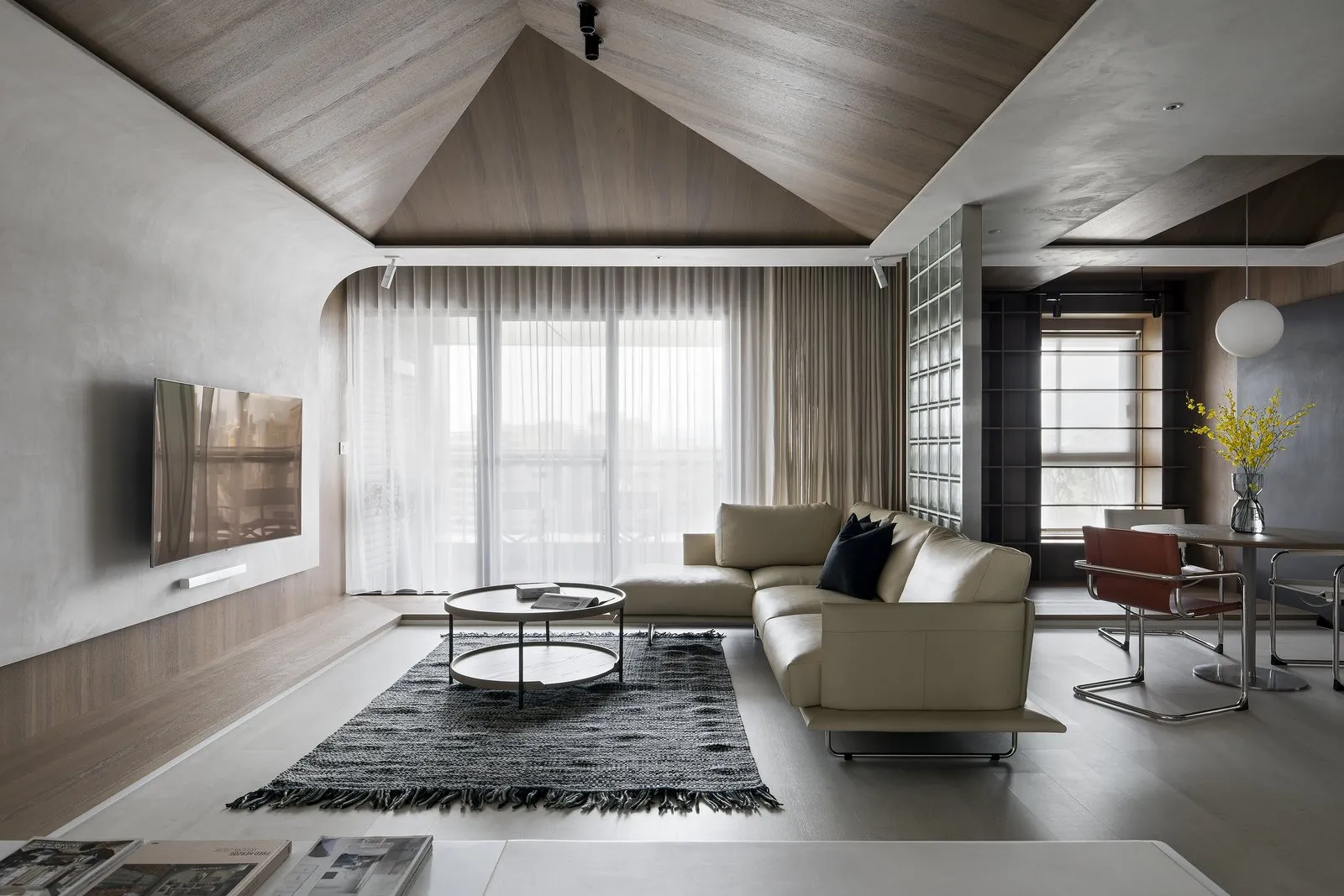 A modern, minimalist living room with concrete aggregate floors and walls, featuring a comfortable sofa, coffee table, and la