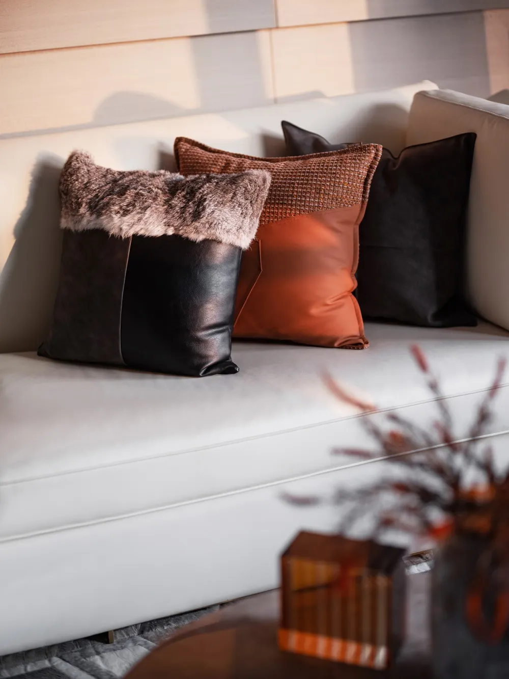 Modern interior cushions with different materials and textures on a couch.