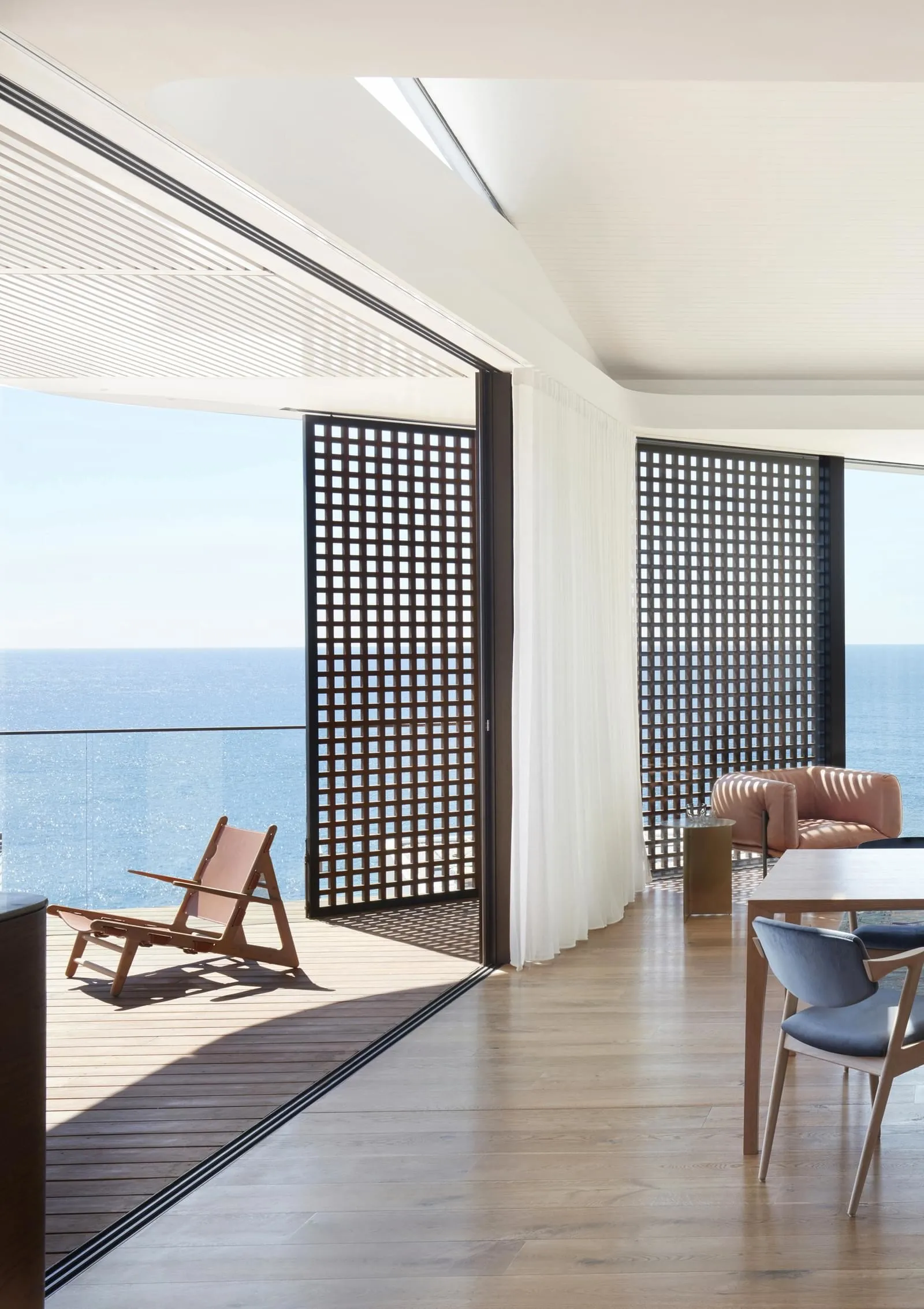 Modern residential interior featuring a sea view, wooden flooring, and contemporary furniture.