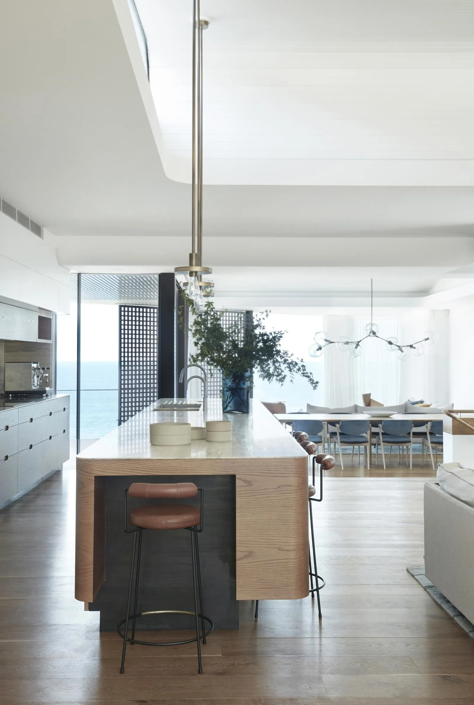 Modern residential kitchen with white marble tile flooring, wooden island, and pendant lighting.