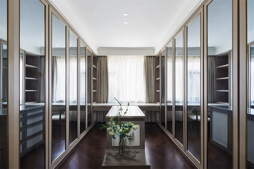 A modern wardrobe with glass doors and dark wooden flooring, featuring sleek lines and minimal design.