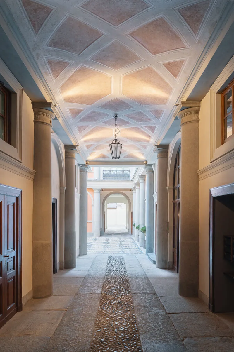 A classical architectural interior with stone columns and concrete floors.