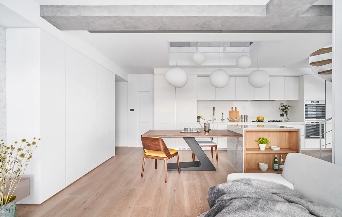 Modern minimalist residential kitchen with marble countertops, wood furniture, and concrete ceiling beams