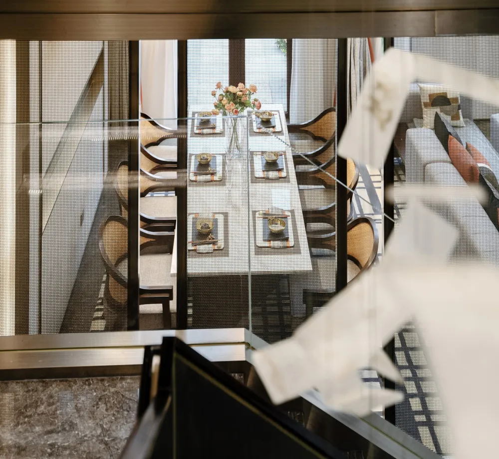 A modern dining room with a glass table and wooden chairs.