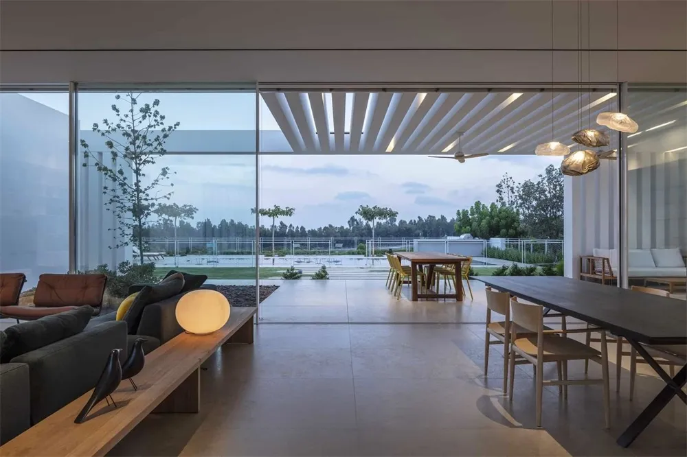 Contemporary living and dining room featuring concrete floors and large glass windows.
