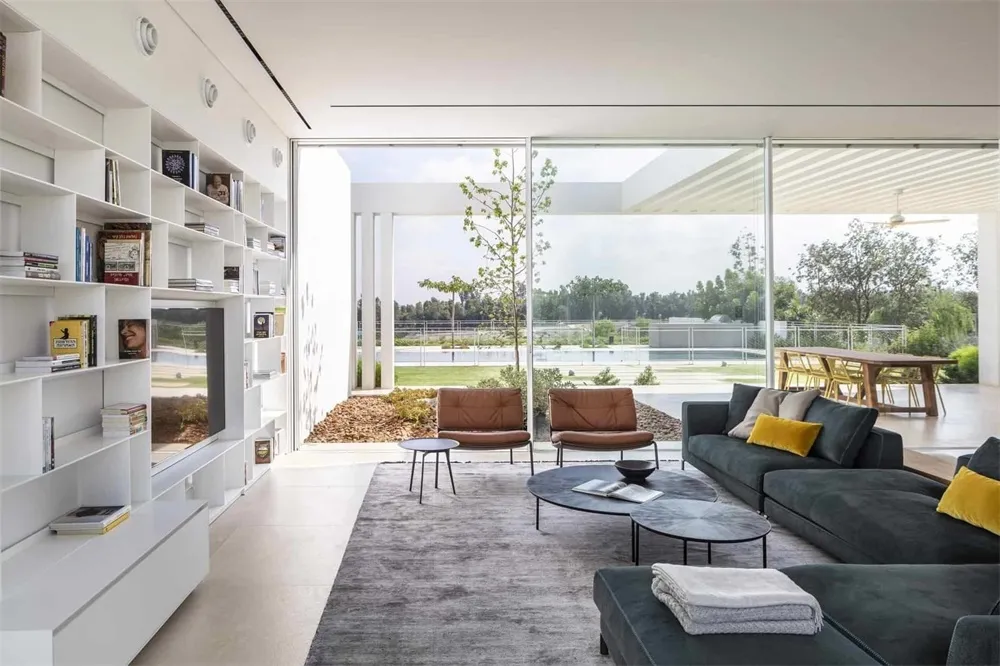 A modern living room featuring glass walls, canvas seating, and cement flooring.