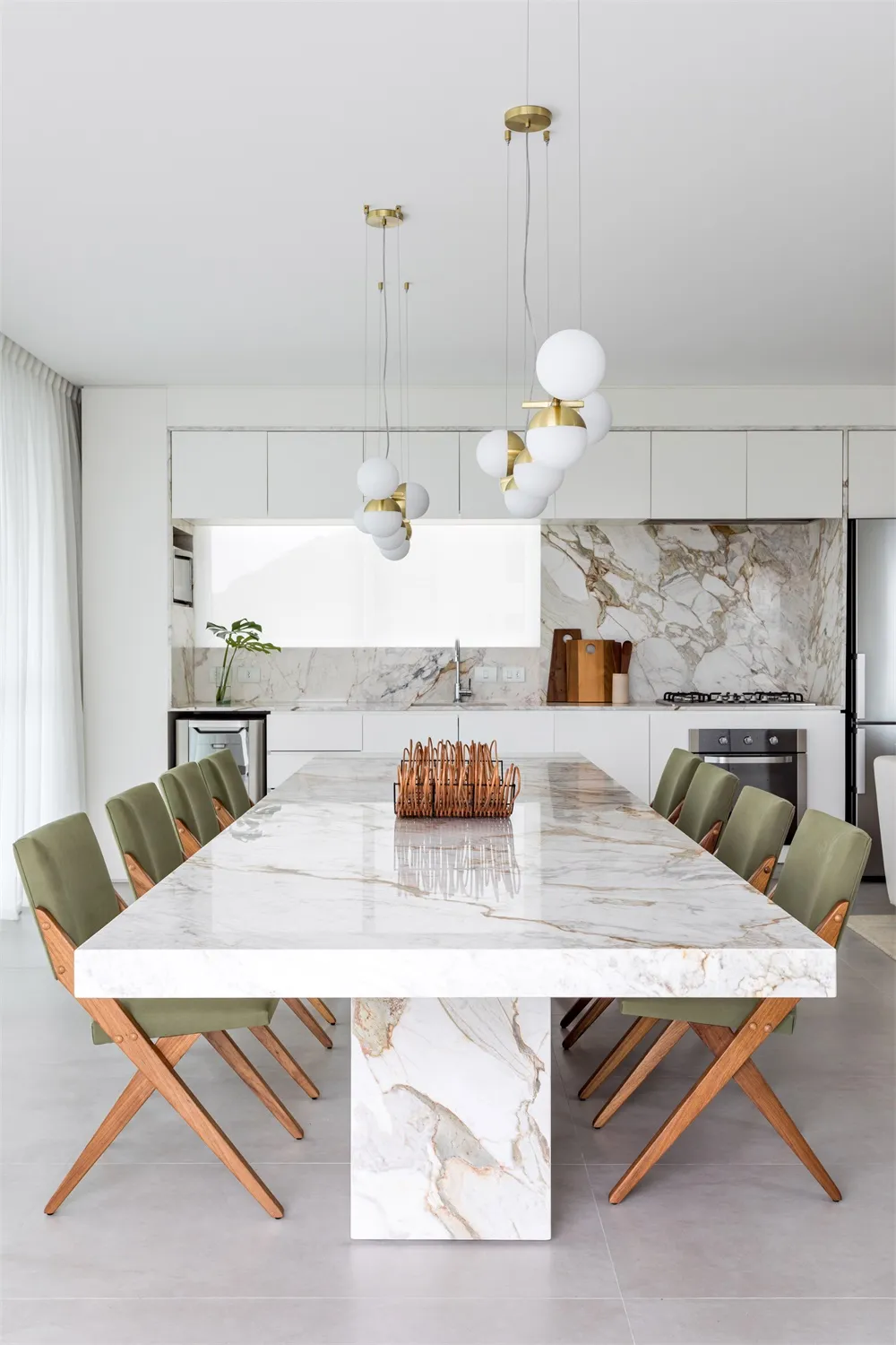 A modern kitchen with a marble countertop and wooden chairs.