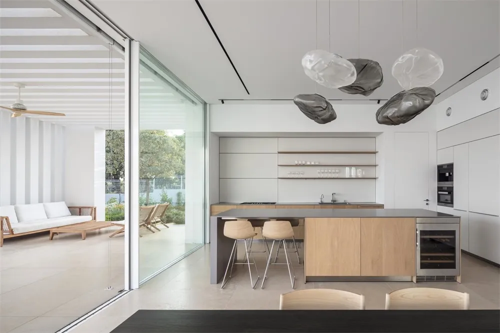Modern, minimalist residential kitchen with wood cabinets, glass countertops, and stainless steel appliances.