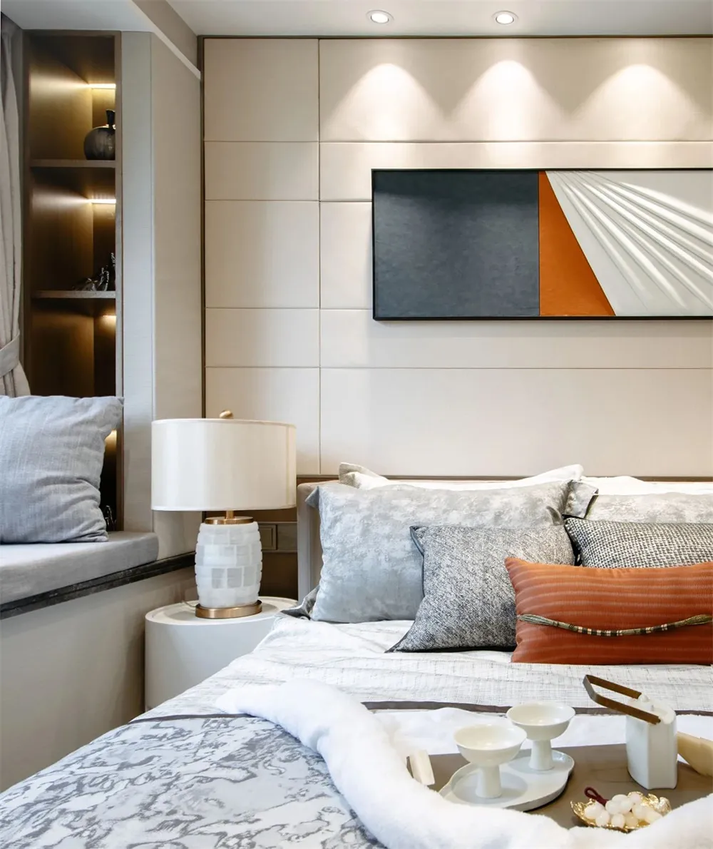 A minimalist bedroom featuring a bed with marble and fabric textures, complemented by a marble lamp and a wall-mounted abstra