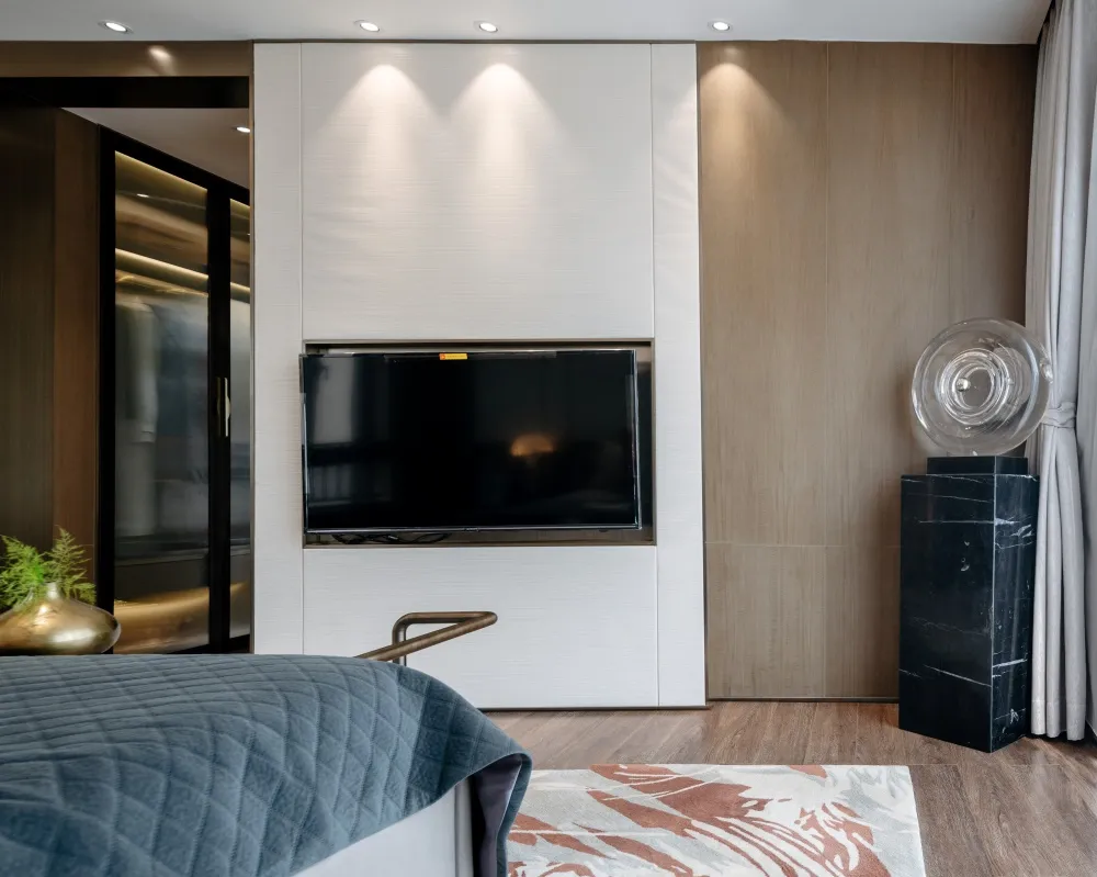 Modern bedroom with wooden and glass walls, and metallic furniture, featuring a large flat-screen TV mounted on the wall