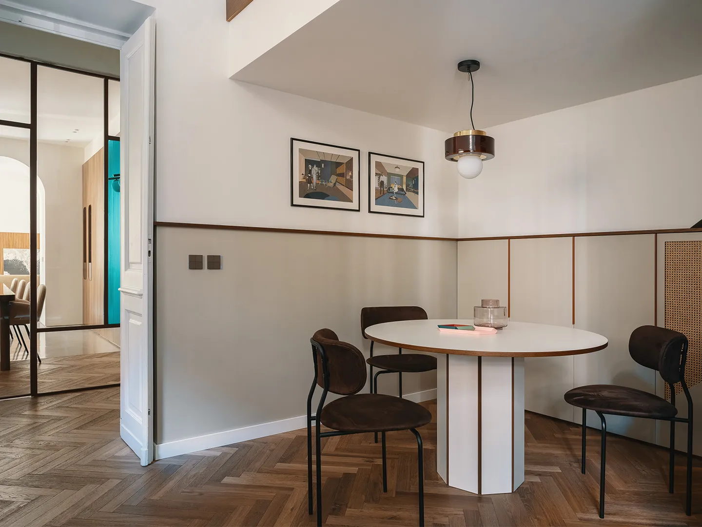 Modern dining room with wooden flooring, glass table, and metal chairs.
