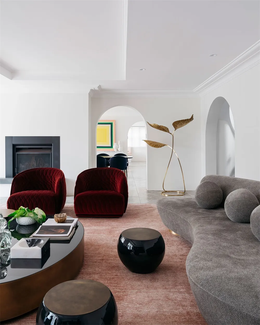 A modern living room with a velvet upholstered sofa, a round wooden coffee table, a black and white marble side table, and a