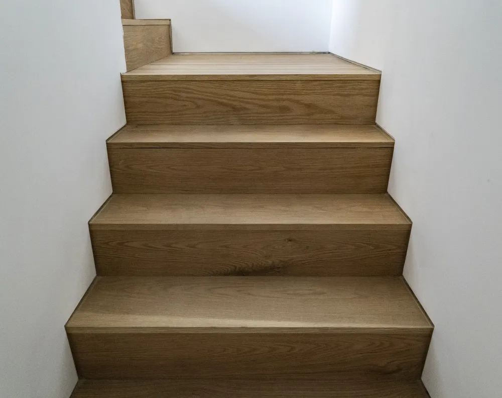 Modern, wooden staircase with light-colored wood panels.