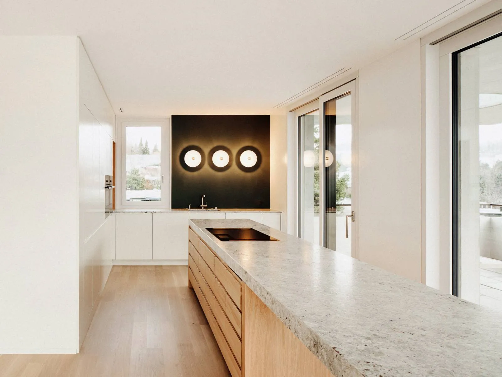 A modern kitchen featuring a marble countertop and wooden cabinets.