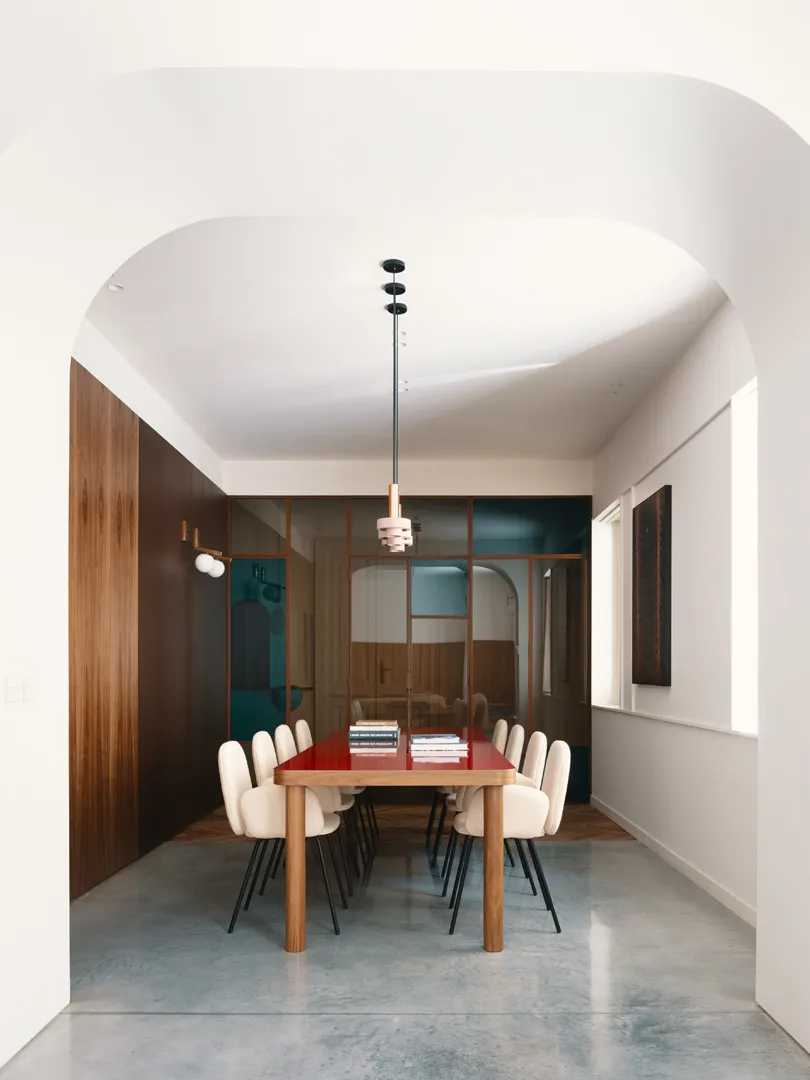 An office space with a modern design featuring a wooden table, concrete flooring, and glass partitions.