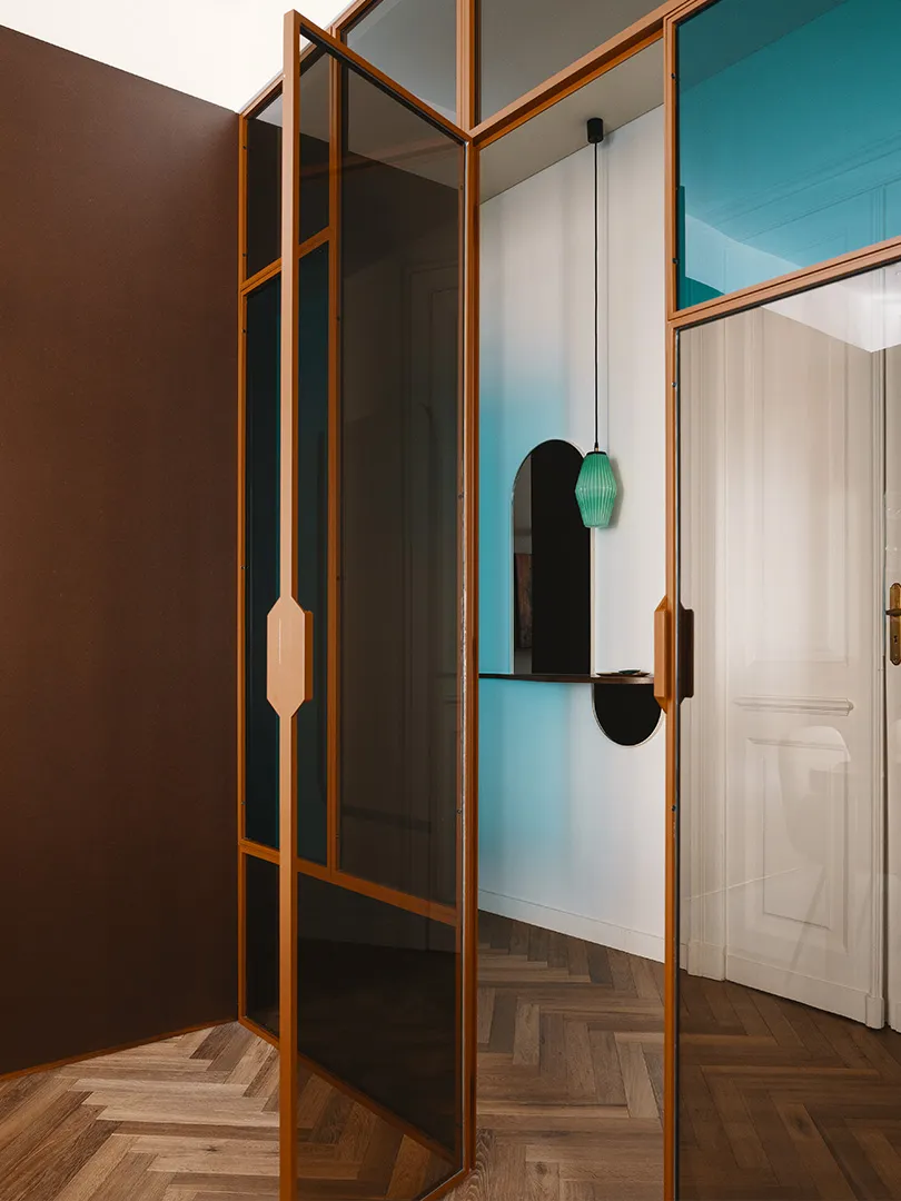 A modern residential glass door with metallic accents on a wooden floor.