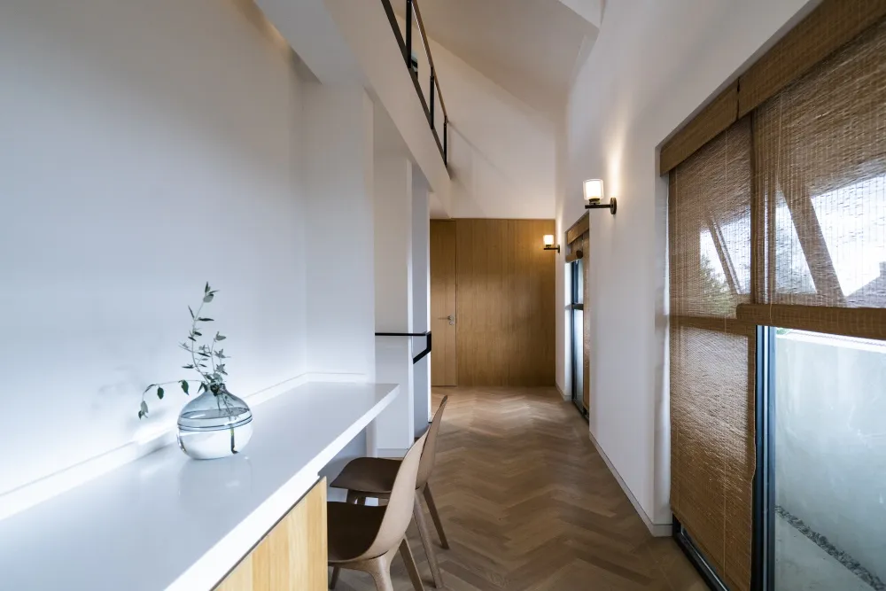 Modern minimalist residential interior with wooden flooring, glass walls, and metallic accents