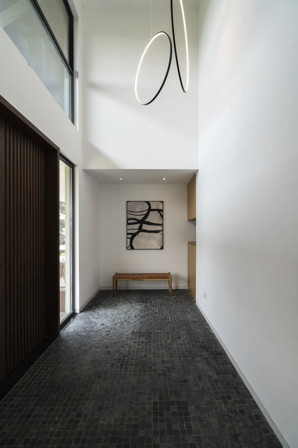 Modern entryway featuring black tiled flooring, minimalist decor, and contemporary lighting.