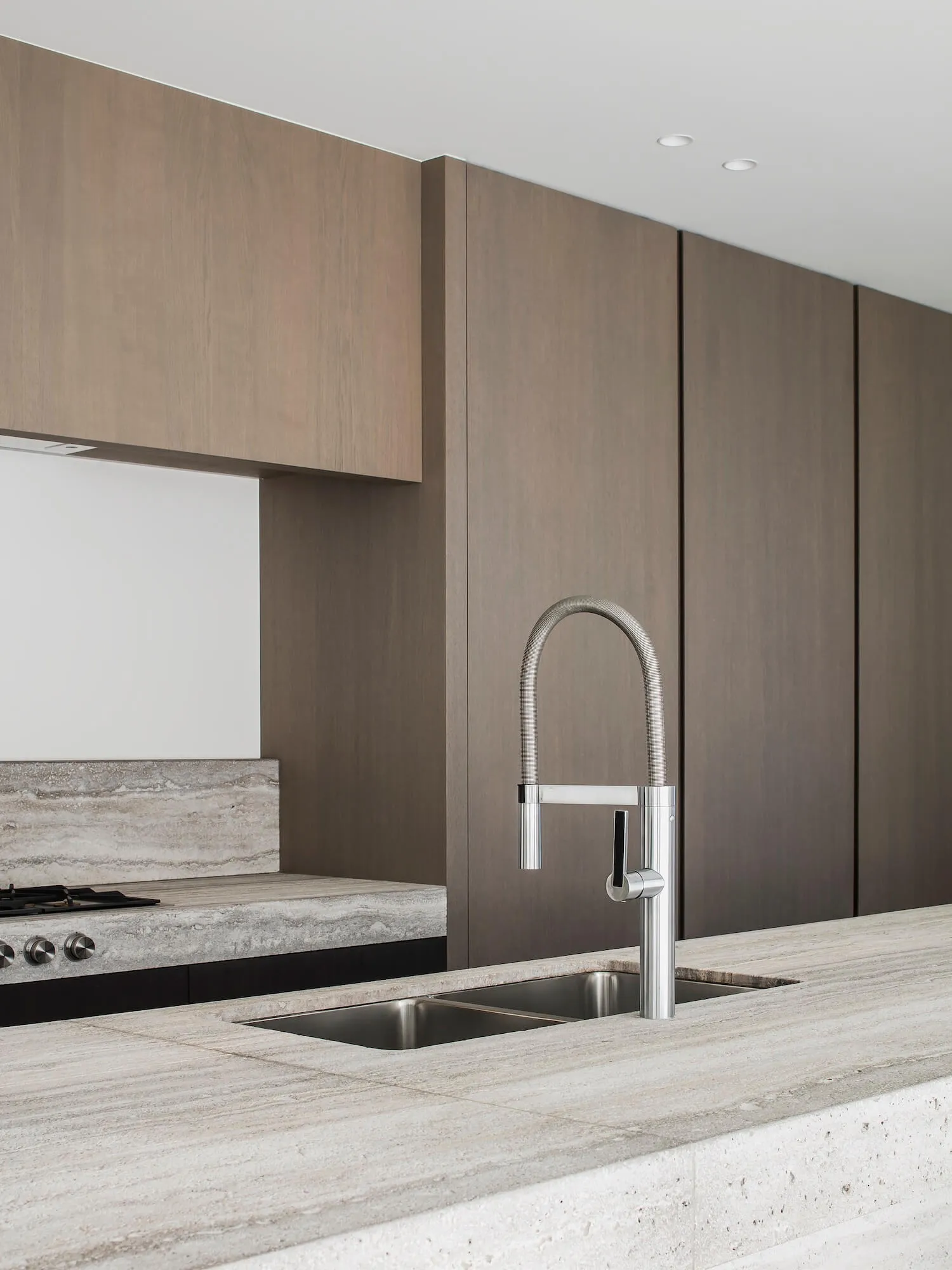 A modern kitchen with a stone countertop and a waterfall edge sink.