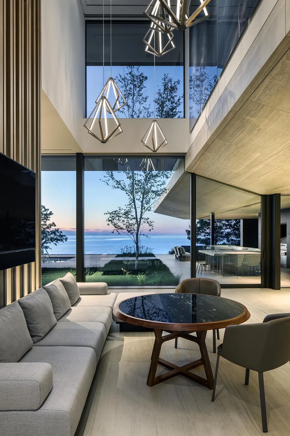 A modern living room featuring concrete and glass materials with a large window overlooking the sea.