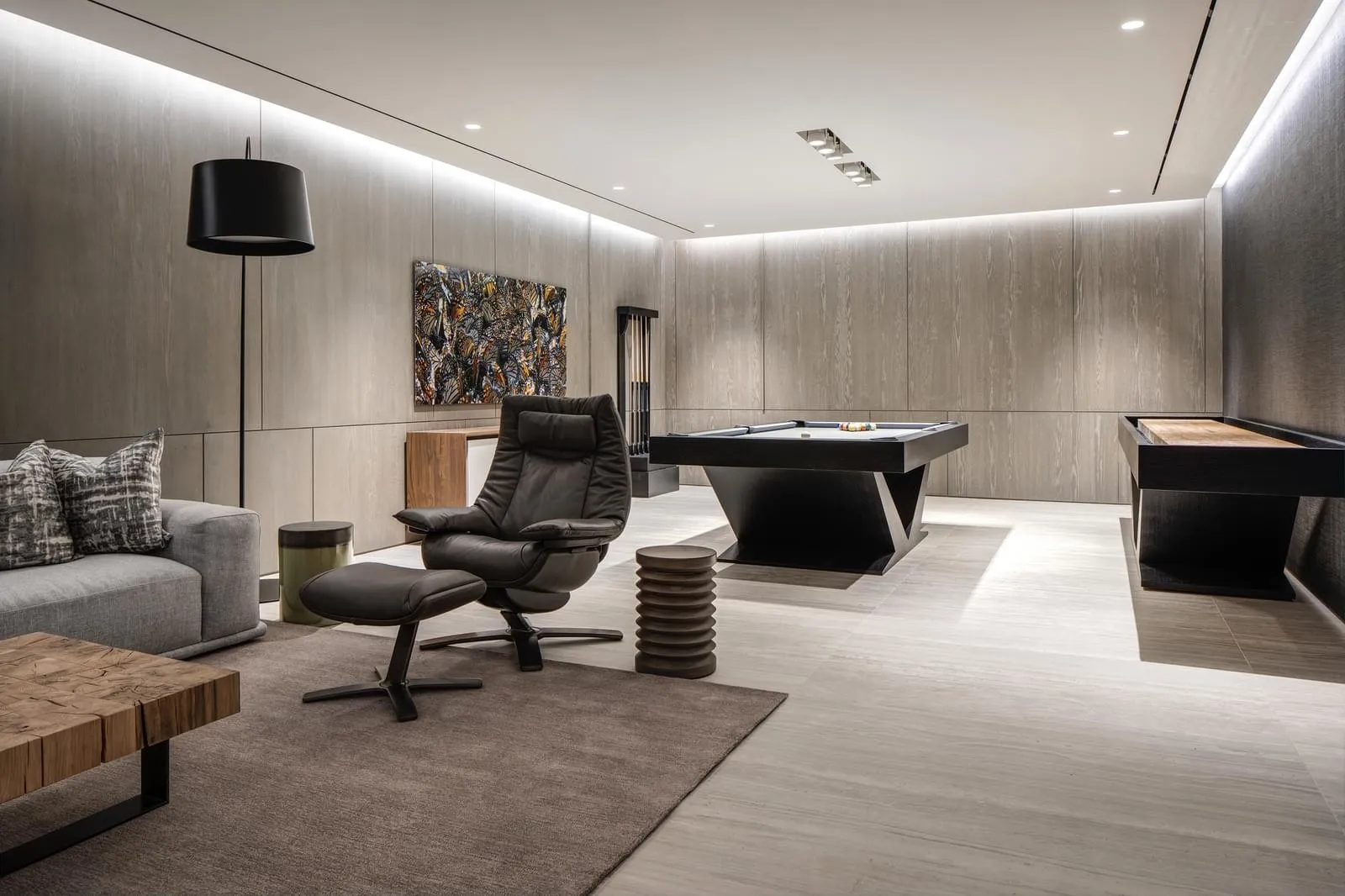Modern living room featuring a contemporary leather recliner chair, wooden coffee table, and a sleek black pool table with bi