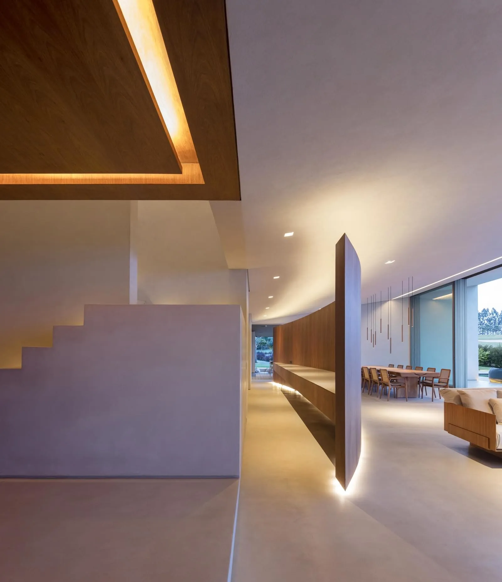 A modern, minimalist residential interior with concrete walls and floor, minimalist furniture, and warm lighting.