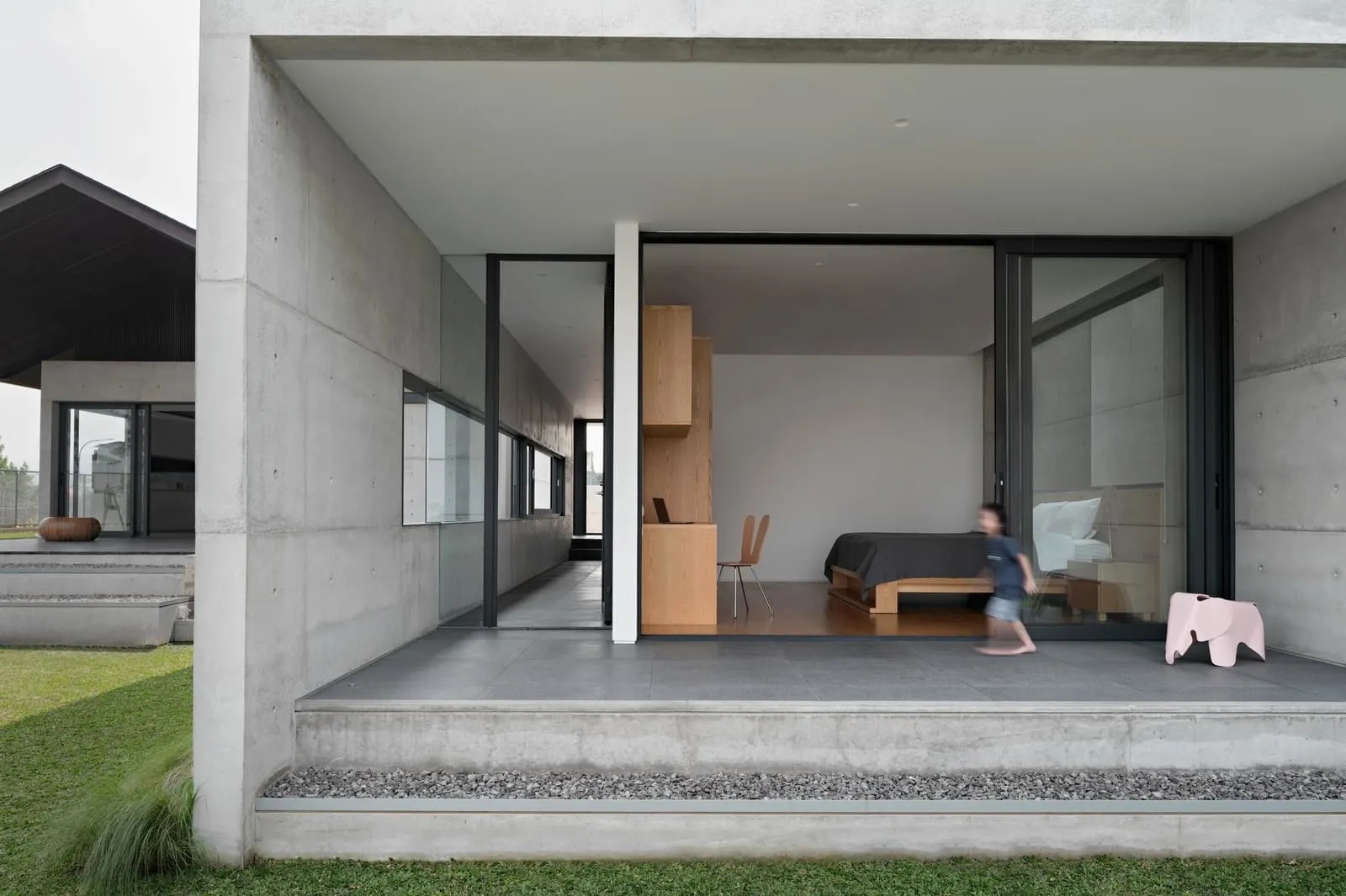Modern minimalist bedroom with concrete walls, wooden furniture, and glass windows.