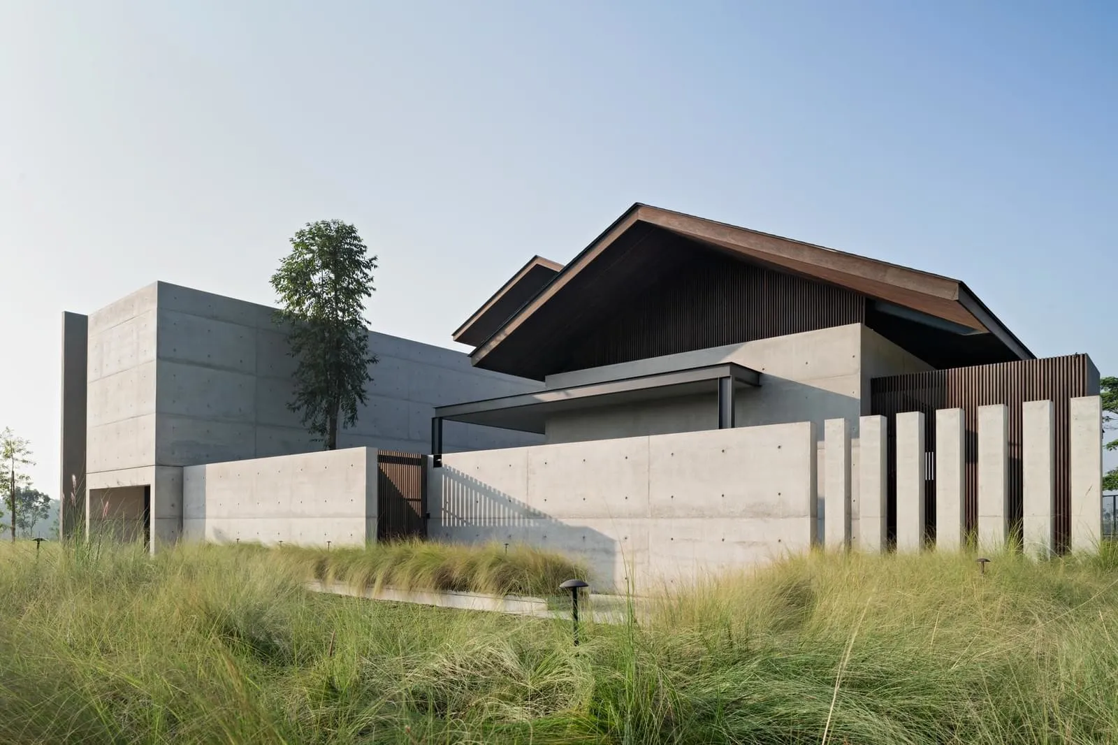 Large modern residential building with concrete exterior and greenery surrounding it.