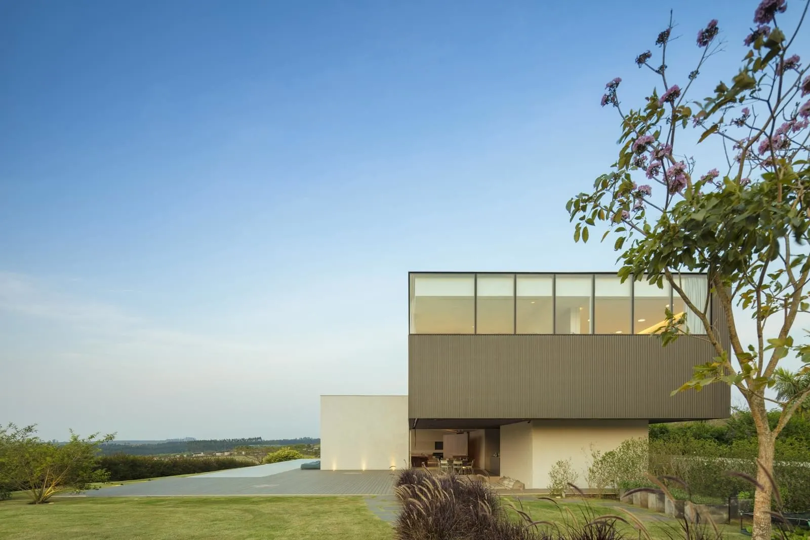 Modern residential house with glass cladding and large windows.